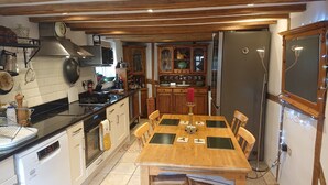 A kitchen with wooden cabinets, a dining table with chairs, a refrigerator, and a stove.