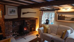 A cozy living room with a brick fireplace, a sofa, and a window with curtains.