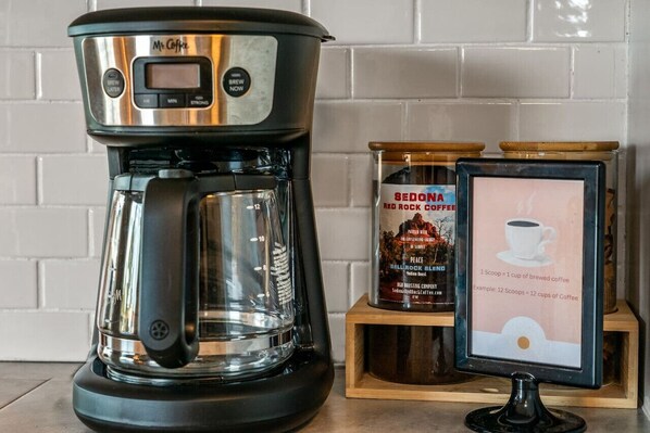 Una macchina da caffè con display digitale, un contenitore per caffè e un'illustrazione di una tazza di caffè incorniciata.