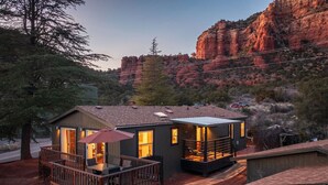 A small cabin with a deck and a fireplace, surrounded by natural scenery and a mountain backdrop. - Sedona`s Oceanfront Property • Spa, Views, Trails! (Sedona)