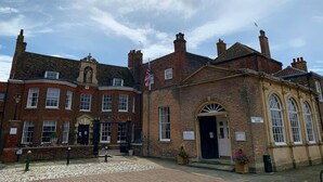 A historic building with a prominent entrance, a flag, and a sign indicating 'Kings Staithe Square'.