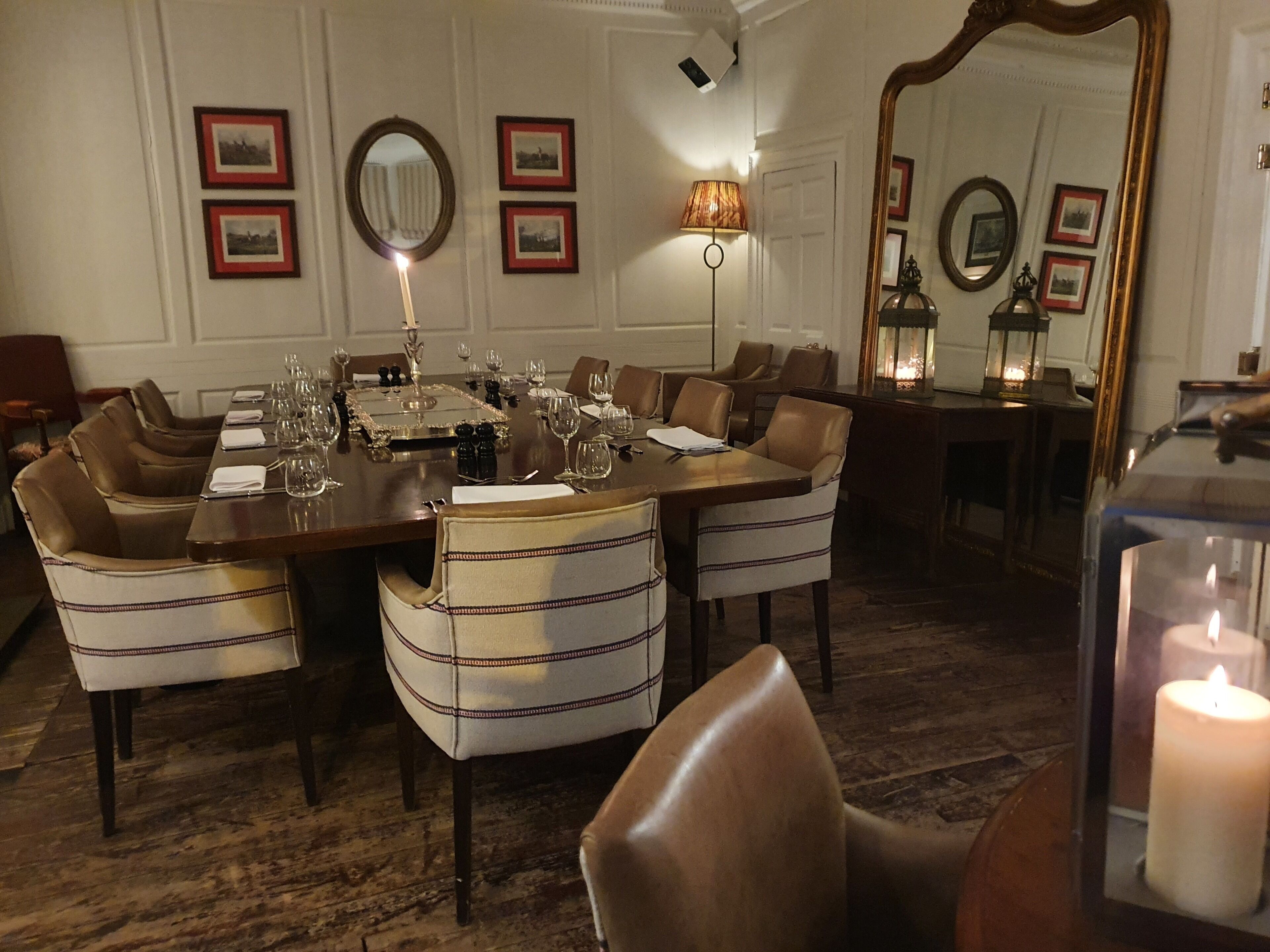 A dining area with a long table set for a meal, surrounded by upholstered chairs.