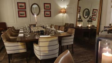 A dining area with a long table set for a meal, surrounded by upholstered chairs.