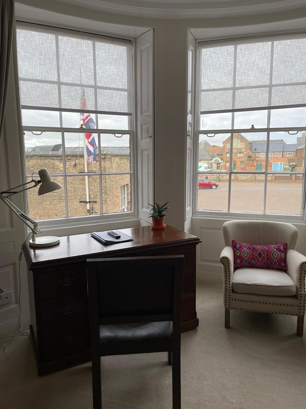 A room with a desk, chair, and two windows.