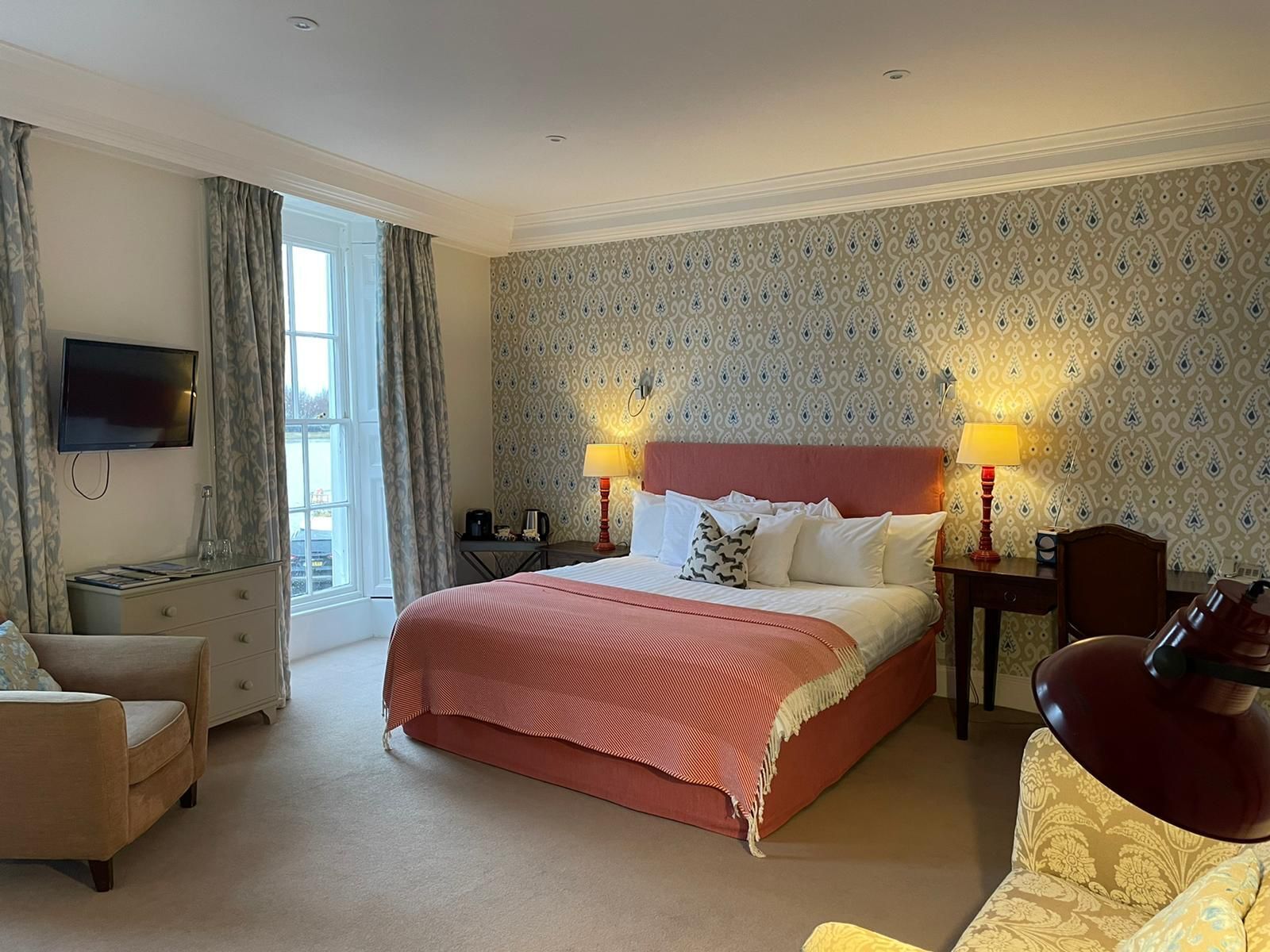Une chambre d’hôtel avec un grand lit, deux lampes de chevet, une télévision, un bureau et une chaise.