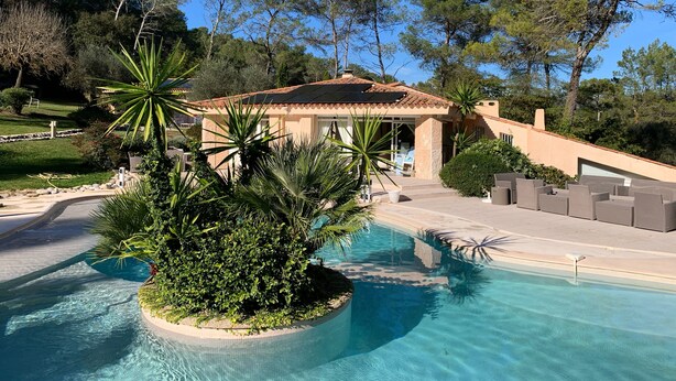 A pool area with a house in the background, surrounded by trees and greenery. - Large 600M2 property, tennis and 60sqm pool house with bar-kitchen on 10000 sqm (Mougins)