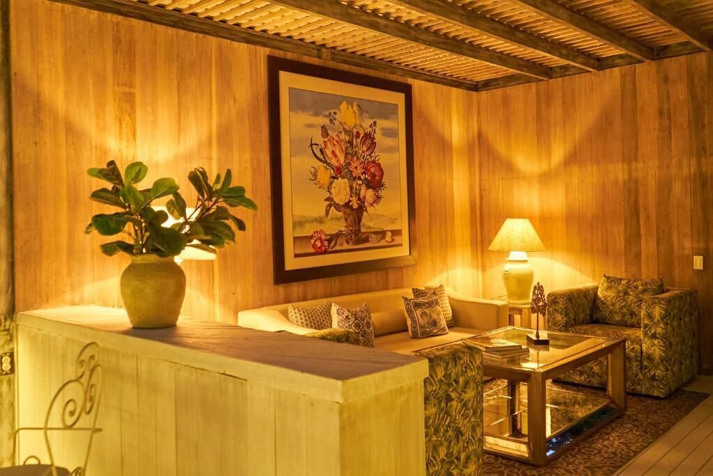A cozy room with a wooden wall, a sofa, a coffee table, a lamp, and a potted plant.