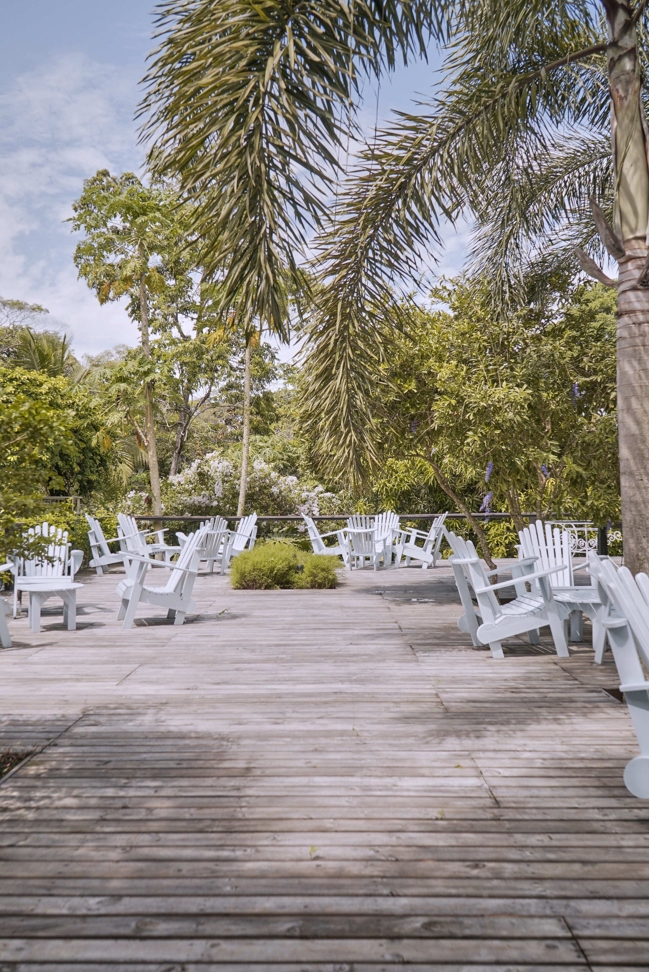 A wooden deck with white chairs arranged for seating.