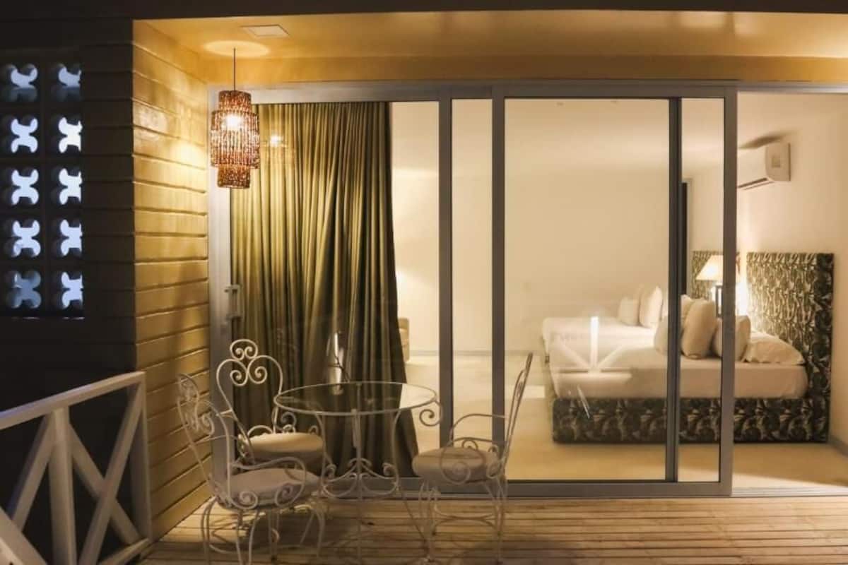 Una habitación con cama, una silla, una mesa y una cortina.