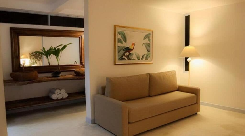 Ein Wohnzimmer mit einer Couch, einer Lampe, einem gerahmten Bild und einer Pflanze auf einem Regal.
