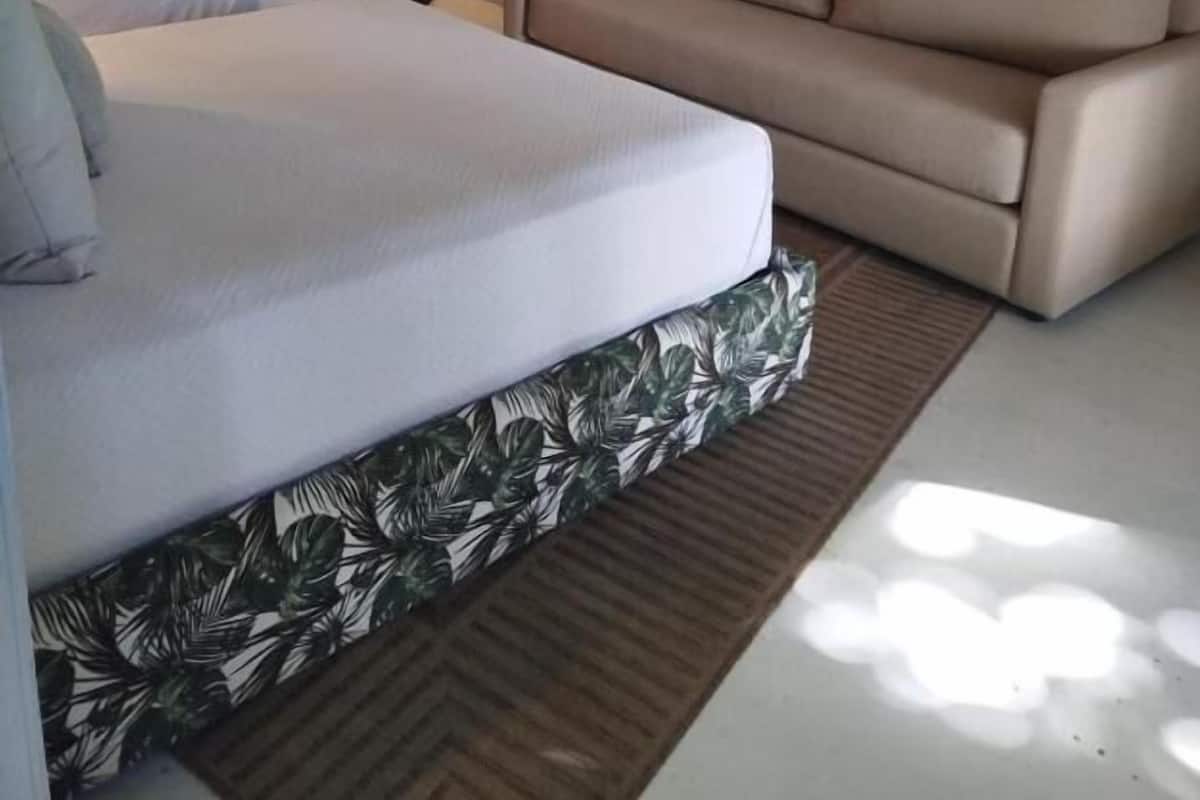 Una habitación de hotel con cama, sofá, lámpara de pie y puerta.
