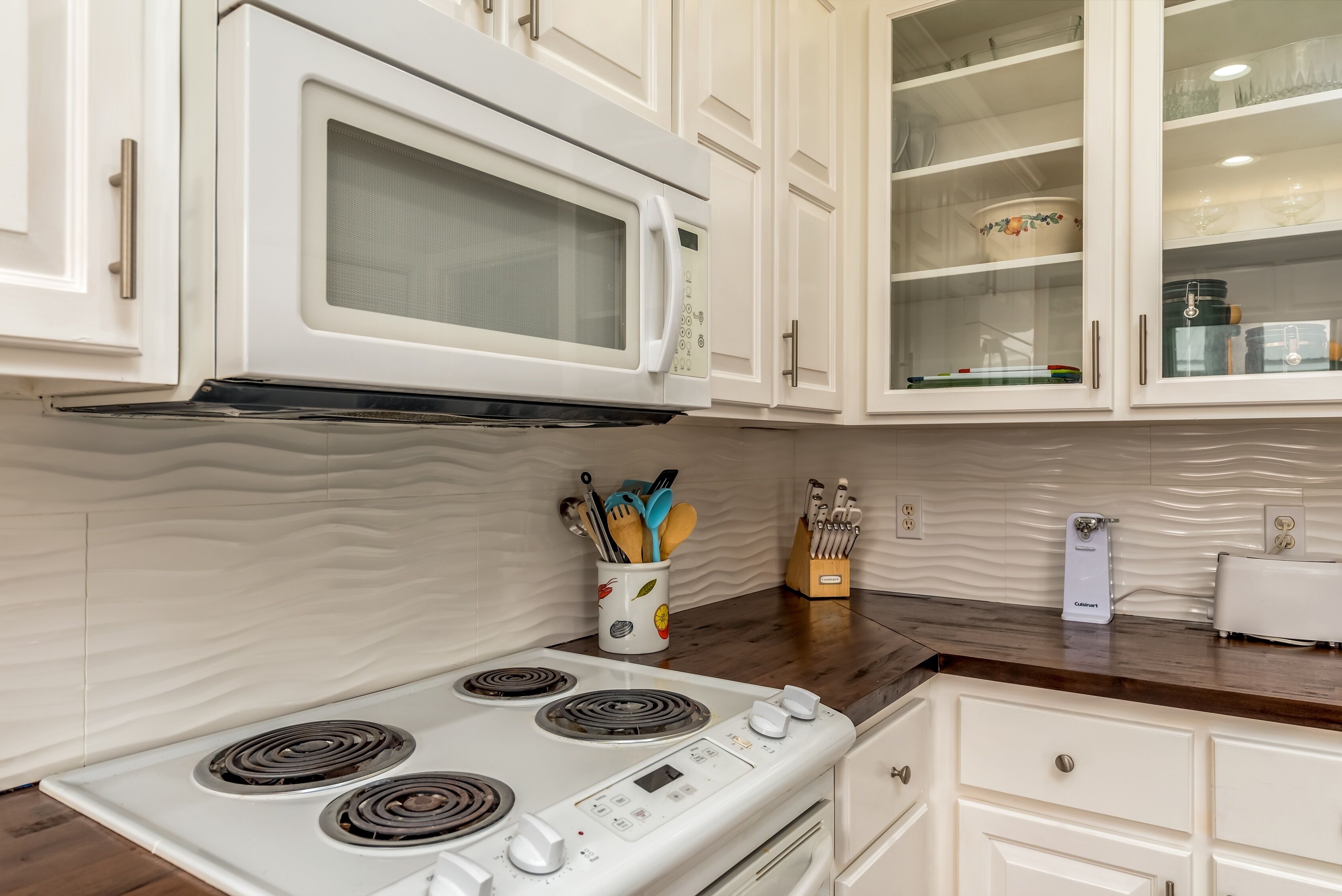 A kitchen with white cabinets, a microwave, a stove, and a toaster.