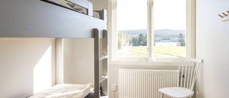 A bunk bed room with a view of a lake and hills.