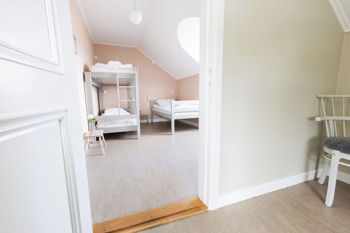 Ein Schlafzimmer mit Etagenbetten, einem kleinen Tisch mit Pflanze und einem Sessel.