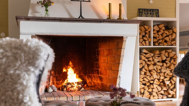 Una sala de estar acogedora con chimenea, una pila de leña y un mobiliario confortable.