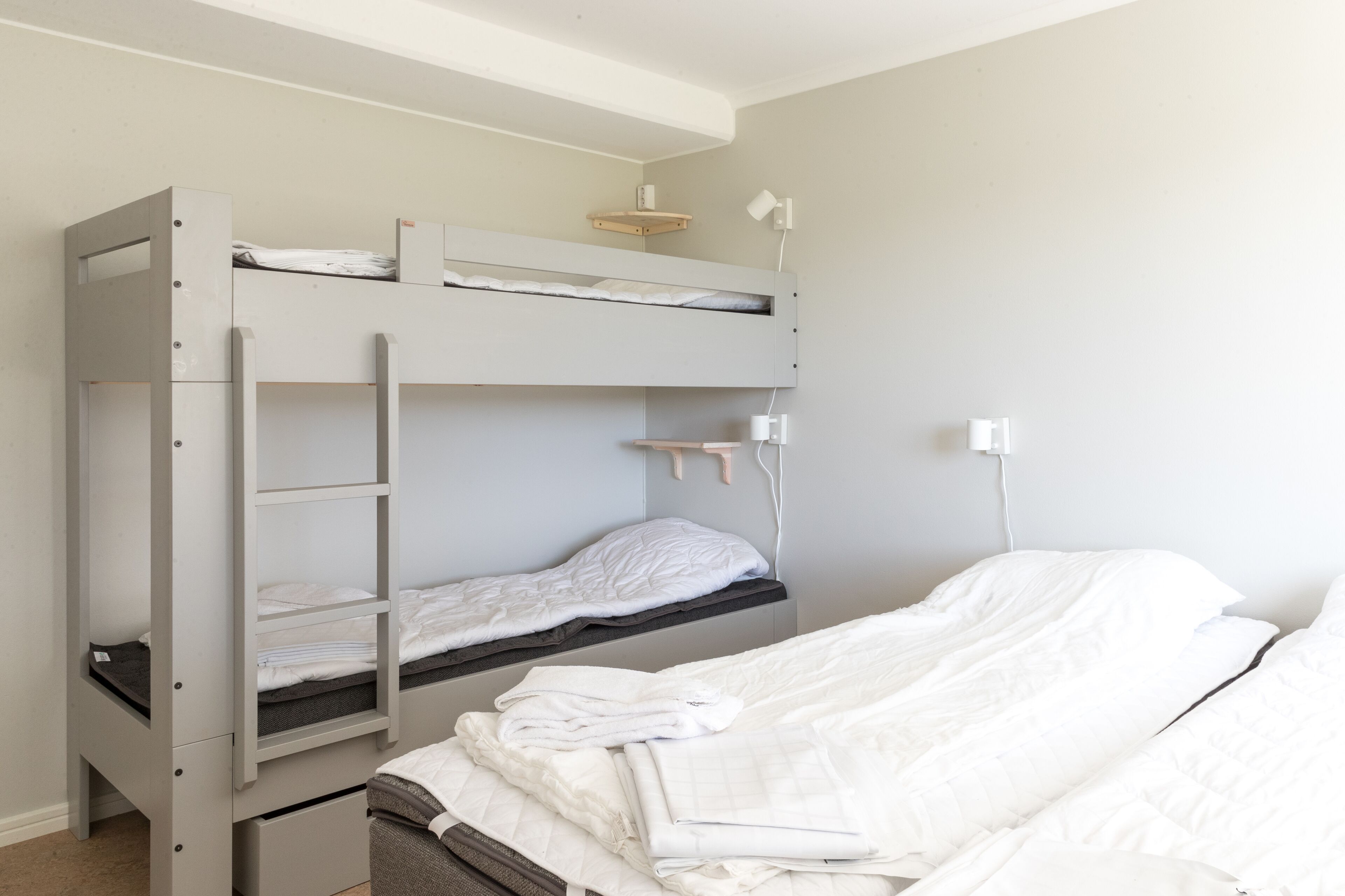 Une chambre avec un lit superposé, un bureau et une lampe.