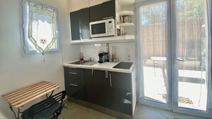 A compact kitchen with a microwave, sink, and a bench.