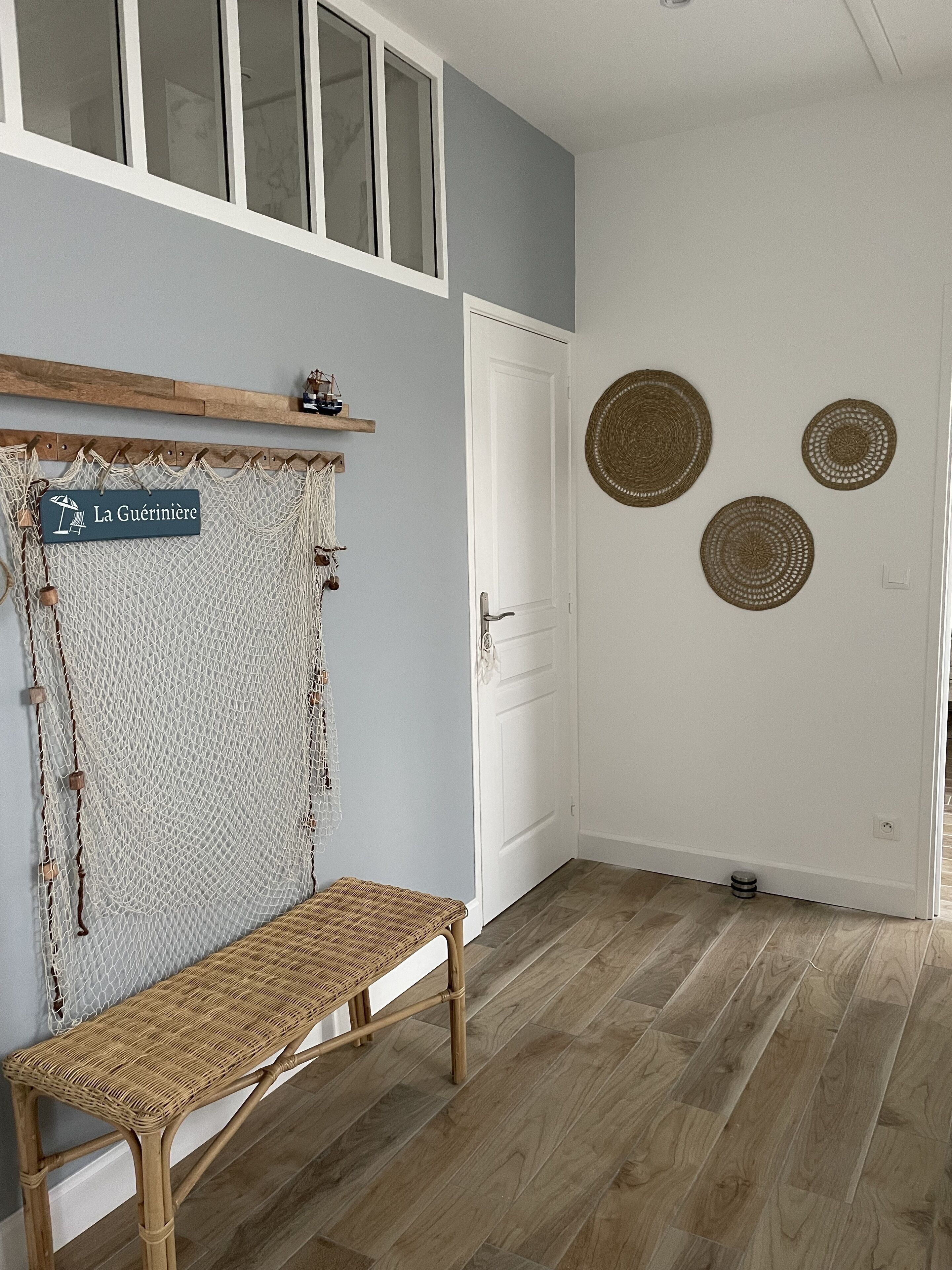 Une pièce comprenant un banc en osier, une porte et trois éléments de décoration murale tissés.