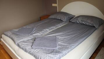 A single bed with a white headboard and grey bedding.