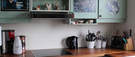 Una cocina con armarios verde azulado, una cafetera y un hervidor sobre la encimera.