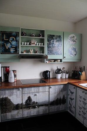A kitchen with teal cabinets, a coffee maker, and a kettle on the counter.
