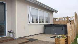 A wooden deck with a wooden planter box, a window, and a door. - Stóri-Bakki Guesthouse with hot tub (Egilsstaðir)