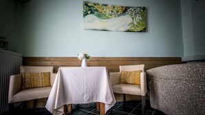 A room with a wooden bench, a table with a white tablecloth, and a floral-patterned bed. - Daphne House In Pelion (Zagora-Mouresi)