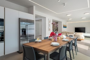 A modern kitchen with a dining area, a sofa, and a TV in the living room.