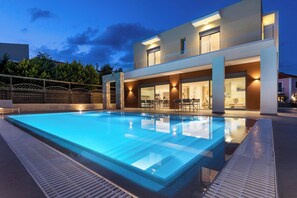 Un hôtel moderne doté d’une piscine, d’un espace extérieur aménagé et d’une entrée bien éclairée.