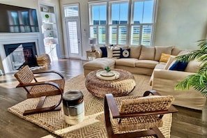A living room with a fireplace, a sofa, a coffee table, and a large window with blinds.