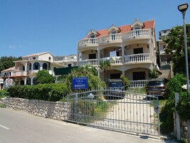 Un edificio a più piani con balconi, un muro in pietra e un ingresso carrabile.