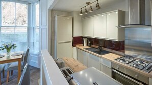 Una cocina moderna con estufa a gas, muebles de acero inoxidable y un comedor con mesa y sillas.