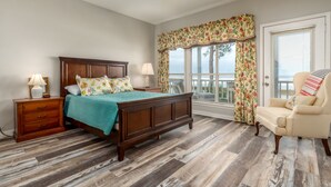 Un dormitorio con una cama de madera, una mesita de noche, una silla y una ventana con cortinas florales.