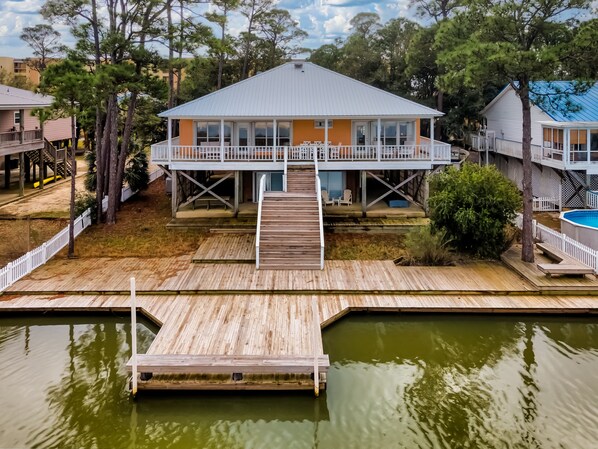 A house with a deck, a dock, and a pool.
