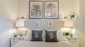 A neatly arranged bedroom with a large bed, two bedside tables with lamps, and framed botanical prints on the wall. - Casa Uccellini in Lucca (Lucca)