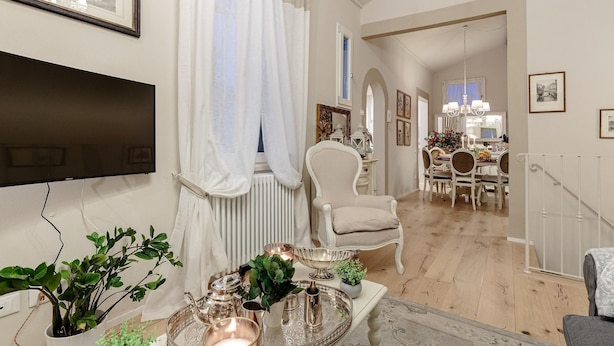 A living room with a flat-screen TV, a dining area with a chandelier, and a staircase. - Casa Uccellini in Lucca (Lucca)