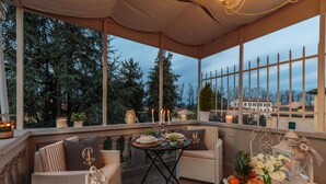 A cozy outdoor seating area with wicker furniture, a table with candles, and a view of trees and buildings. - Casa Uccellini in Lucca (Lucca)
