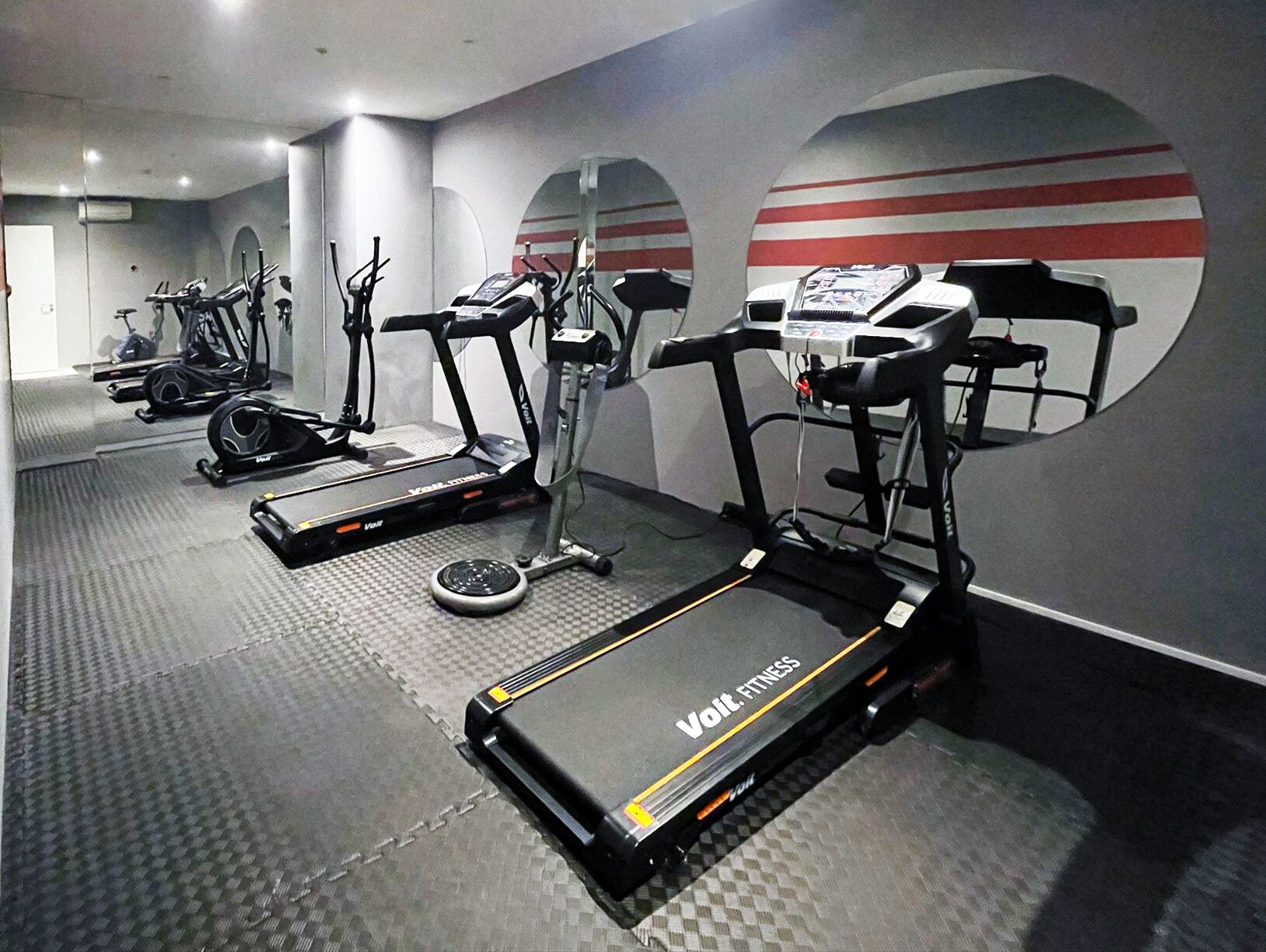 A gym with treadmills, stationary bikes, and elliptical machines.