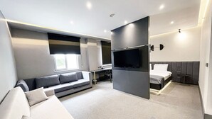 A modern hotel room with a sofa, a bed, a TV, and a desk. - MELLDAY HOTEL (Denizli)
