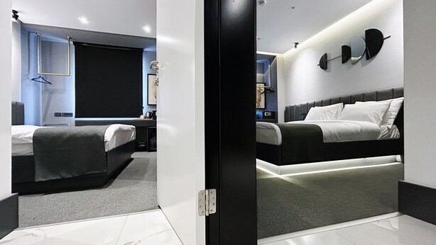 A modern hotel room with a large bed, a smaller bed, a desk, and a seating area. - MELLDAY HOTEL (Denizli)