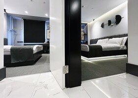 A modern hotel room with a large bed, a smaller bed, a desk, and a seating area.