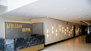 A reception area with a marble counter and a wall displaying 'MELLDAY HOTEL' in gold letters. - MELLDAY HOTEL (Denizli)