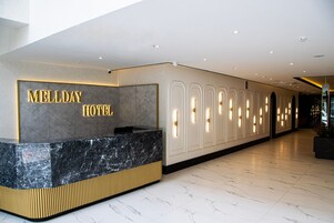 A reception area with a marble counter and a wall displaying 'MELLDAY HOTEL' in gold letters.
