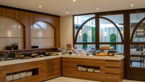 A modern kitchen with a marble countertop, wooden cabinets, and a view of greenery through large windows. - MELLDAY HOTEL (Denizli)
