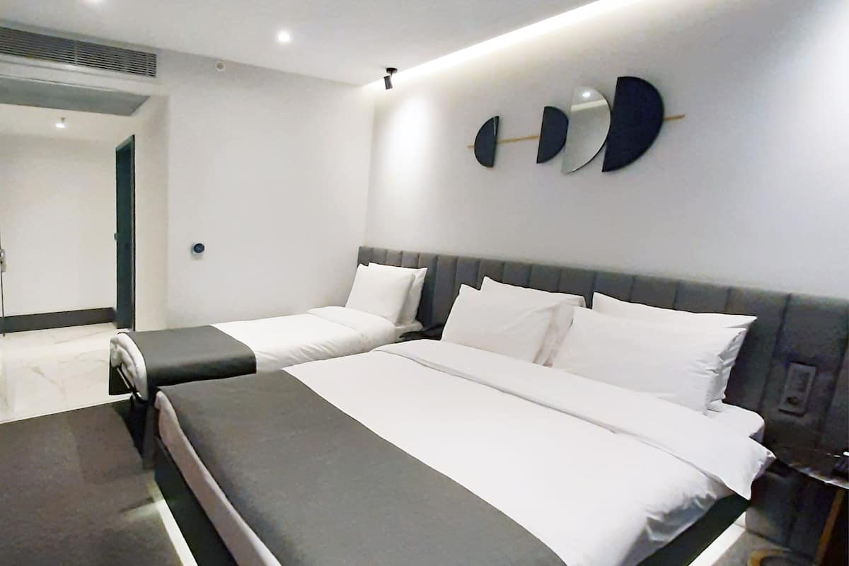 A modern bedroom with a large bed, bedside tables, and a wall-mounted light fixture.