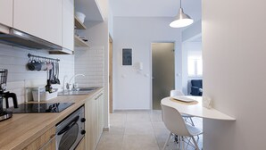 Una cocina moderna con armarios de madera, horno empotrado y comedor con mesa y sillas blancas.