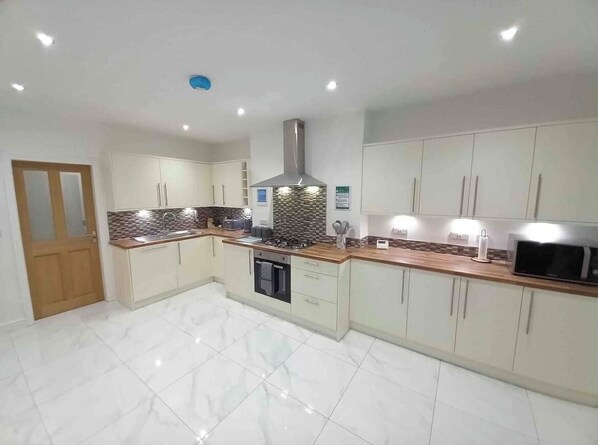 Modern kitchen with light-colored cabinetry, central island, and stainless steel range hood.