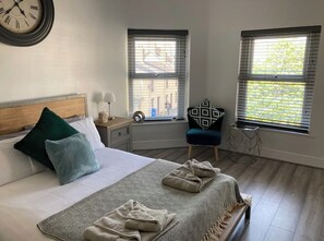 Cozy retreat with a large bed, nightstand, and two lamps, perfect for a restful stay.
