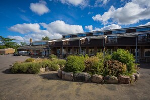 A modern building with multiple units, a parking area, and landscaped garden beds.