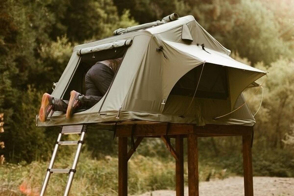 A tent set up on a wooden stand in a forested area.